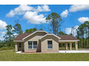 Charming one-story home features a welcoming covered carport, well-manicured lawn and neutral color palette at 13491 E Hwy 316, Fort Mc Coy, FL 32134