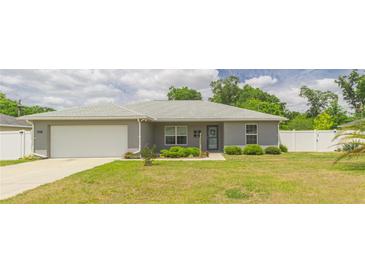 Charming single-story home boasts a well-manicured front yard and an attached two-car garage at 1453 Ne 161St Pl, Citra, FL 32113