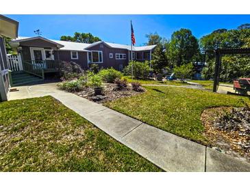 Inviting home featuring a lush lawn, garden areas and mature trees, perfect for enjoying outdoor living at 20906 River Dr, Dunnellon, FL 34431