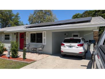 Charming single-story home featuring solar panels, a red front door, and cozy carport at 2219 Ne 18 Ave, Ocala, FL 34470