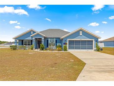 Charming single-story home featuring a beautiful blue exterior, well-manicured lawn, and an attached two-car garage at 4881 Se 91St Pl, Ocala, FL 34480