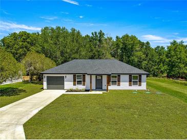 Charming single-story home with a well-manicured lawn and attached garage, perfect for suburban living at 10605 Se 146Th Ln, Summerfield, FL 34491
