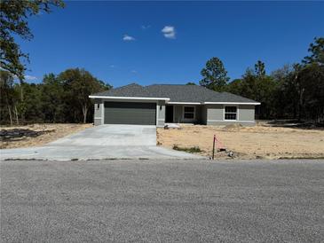 Charming single-story home featuring a gray exterior, concrete driveway, and a well-manicured lawn at 1233 Sw Winding Hills Rd, Dunnellon, FL 34431
