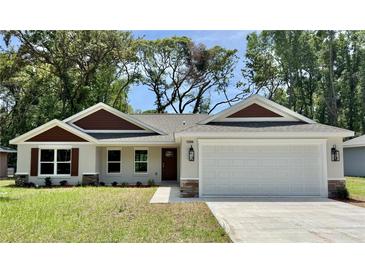Charming home featuring a two-car garage, landscaped yard, and stone accents at 13506 Sw 114Th Ln, Dunnellon, FL 34432