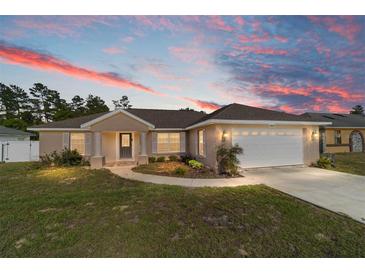 Charming single-story home with a two-car garage, landscaped front yard and colorful sunset at 14085 Sw 34Th Terrace Rd, Ocala, FL 34473