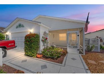 Charming home featuring a landscaped yard, an American flag, and a cozy screened-in porch at 2693 Craven Way, The Villages, FL 32162