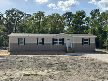 Charming single story home featuring horizontal siding, black shutters, and a front entrance with stairs at 6658 Sw 165Th Ct, Ocala, FL 34481
