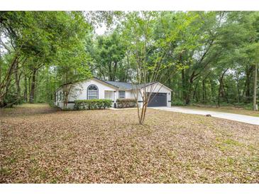 Charming single-story home featuring a well-maintained front yard and attached two-car garage in a wooded setting at 7585 Sw 79Th Pl, Ocala, FL 34476