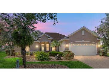 Charming single-story home with a well-manicured lawn, mature trees, and a two-car garage, captured during the evening at 8632 Sw 86Th Cir, Ocala, FL 34481