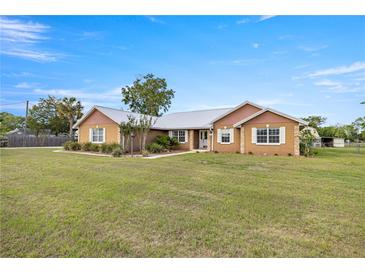 Charming single-story home with a sprawling lawn and white-trimmed windows and a metal roof at 719 Ne 39Th St, Ocala, FL 34479