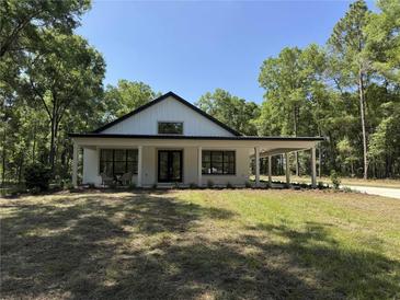 Charming single-story home with modern farmhouse design, lush lawn, and inviting covered porch at 18890 Sw 60Th St, Dunnellon, FL 34432