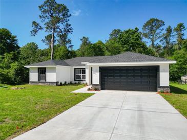 Charming single-story home with a well-manicured lawn, dark garage door, and a modern design at 2376 Se 40Th Street Road, Ocala, FL 34480