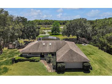 Lovely single-story home on a sprawling green lawn with mature trees and an enclosed pool in the backyard at 26200 Se Highway 42, Umatilla, FL 32784