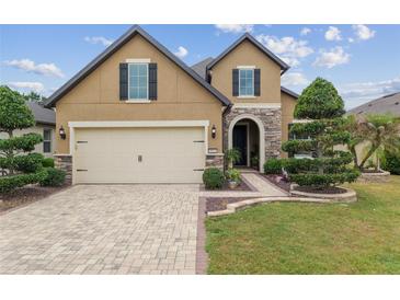 Charming two-story home featuring a brick driveway, manicured lawn, and stone accents on the facade at 6816 Sw 95Th Cir, Ocala, FL 34481