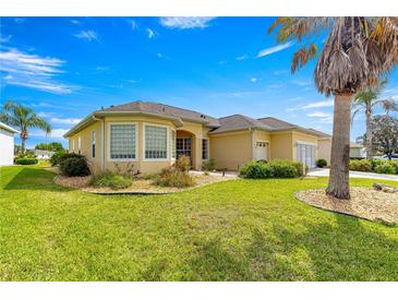 Well-maintained front yard with lush green grass and mature landscaping surrounds a light yellow single-story home at 11799 Se 173Rd Lane Rd, Summerfield, FL 34491