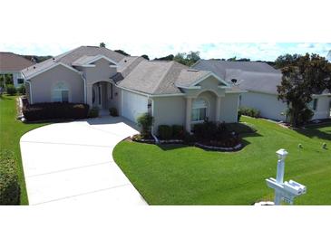 Charming home with a well-manicured lawn, lush landscaping, and a curved driveway leading to an attached two car garage at 2323 Nw 55Th Avenue Rd, Ocala, FL 34482