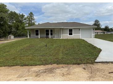 Charming single-story home with a fresh lawn, inviting front porch, and attached garage at 21 Pl # 14443, Ocala, FL 34481