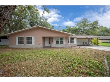 Charming single-story home with a well-manicured lawn, covered porch, and attached carport at 660 Silver Pass, Ocala, FL 34472