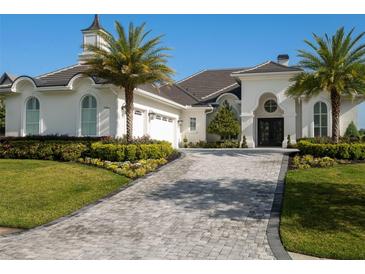 Stunning white home with a dark tile roof, a circular window over the entry, and a decorative driveway at 7585 Nw 33Rd Pl, Ocala, FL 34482