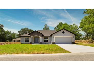 Charming single-story home featuring a two-car garage, well-manicured lawn, and welcoming front entrance at 112 Juniper Run, Ocala, FL 34472