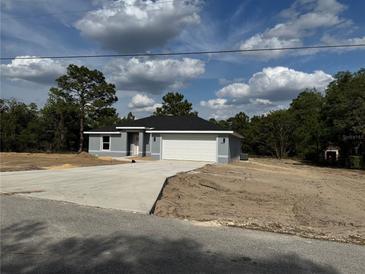 Charming single-story home featuring gray siding, black roof, and a spacious two-car garage with a concrete driveway at 19660 Sw 59Th Ln, Dunnellon, FL 34431