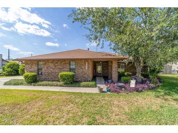 Charming brick home with well-manicured lawn, bushes, and a beautiful tree in the front yard on a sunny day at 2045 Se 32Nd St, Ocala, FL 34471