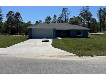 Charming single-story home with a well-manicured lawn, attached two-car garage, and a concrete driveway at 4424 Sw Viola Ct, Dunnellon, FL 34431