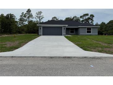 Charming single-story home with a gray exterior, attached garage, and a well-manicured lawn at 4424 Sw Viola Ct, Dunnellon, FL 34431