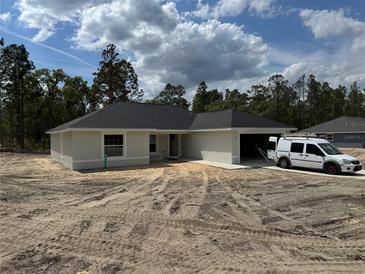 Charming single-story home featuring a spacious driveway and attached garage, surrounded by lush greenery at 4454 Sw Viola Ct, Dunnellon, FL 34431