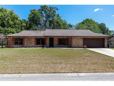 Charming single-story brick home with a well-manicured lawn, shutters, and a two-car garage at 6057 Se 39Th Ave, Ocala, FL 34480