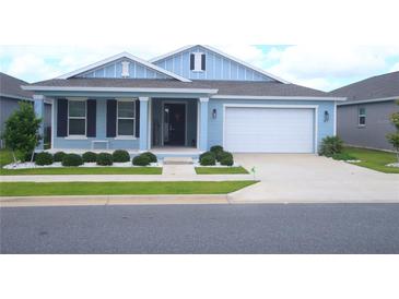 Charming blue home featuring a well-manicured lawn, white rock landscaping, and an attached two-car garage at 7429 Sw 61St St, Ocala, FL 34474