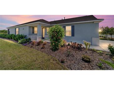 Charming single story home with a manicured lawn and a beautiful flower garden at sunset at 8693 Sw 76Th Ln, Ocala, FL 34481