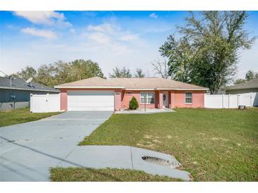 Charming house with a spacious front yard, a large driveway, and a two-car garage at 13425 Sw 106Th Pl, Dunnellon, FL 34432