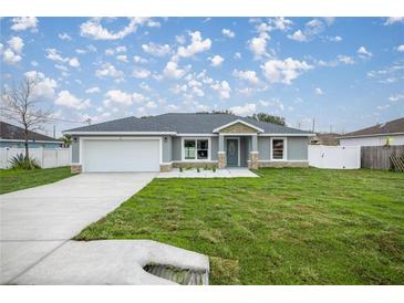 Charming single-story home featuring stone accents, a well-manicured lawn, and a two-car garage at 20751 Sw Cardinal Ave, Dunnellon, FL 34431