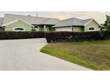 Charming single-story home with a well-manicured lawn, concrete driveway, and lush green landscaping at 2910 Ne 24Th Pl, Ocala, FL 34470