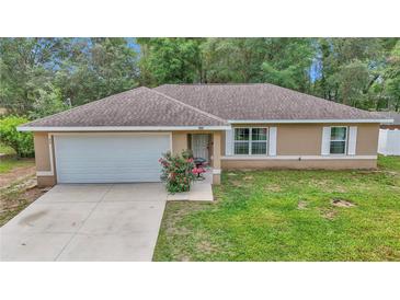 Charming single-story home featuring a well-maintained lawn, attached garage and beautiful landscape at 72 Dogwood Loop, Ocala, FL 34472