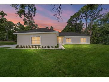 Charming single-story home with lush green lawn, landscaping, and a colorful sunset at 8498 Sw 129Th Terrace Rd, Dunnellon, FL 34432