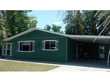 Charming single-story green home with a covered carport and well-maintained front lawn at 9880 Sw 101St Pl, Ocala, FL 34481