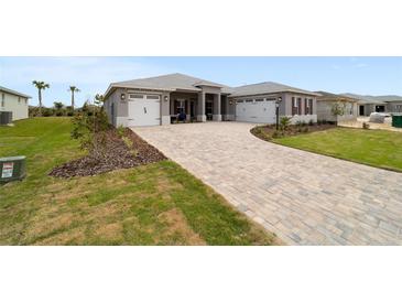Beautiful single-Gathering home featuring a three car garage and a brick-paved driveway and walkway at 10082 Sw 82Nd Place Rd, Ocala, FL 34481
