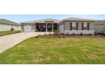 Beautiful single-story home with lush lawn, brick driveway, two-car garage, and meticulously landscaped yard at 10082 Sw 82Nd Place Rd, Ocala, FL 34481