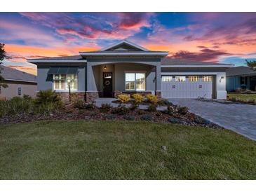 Beautiful home featuring manicured lawn and flowering landscape beneath a dramatic sunset sky at 10327 Sw 96Th Loop, Ocala, FL 34481
