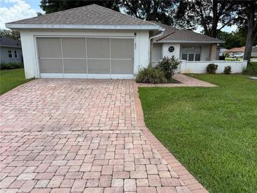 Charming single-story home featuring a brick driveway, well-manicured lawn, and attached garage at 11146 Sw 68Th Ct, Ocala, FL 34476