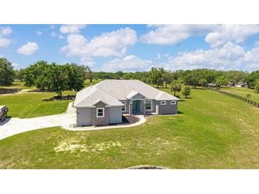 Beautiful single-story home featuring a well-manicured lawn, stylish stone accents and a welcoming, turquoise front door at 5489 Nantahala Ln, Lady Lake, FL 32159