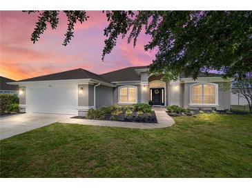 Charming home exterior with a lush lawn, well-maintained landscaping, and inviting entrance at dusk at 9595 Sw 51St Cir, Ocala, FL 34476