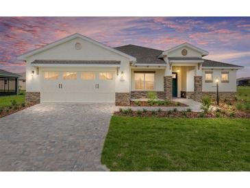 Charming single-Gathering home features a well-manicured lawn, stone accents, and a brick paver driveway at 9871 Sw 105Th Ct, Ocala, FL 34481