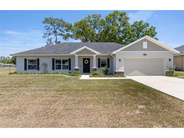 Charming single-story home with a well-manicured lawn and inviting curb appeal under a sunny sky at 10081 Se 68Th Ct, Belleview, FL 34420