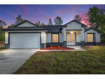 Well-lit single Gathering home featuring a front-facing two-car garage and welcoming front entrance at 12689 Sw 81St St, Dunnellon, FL 34432