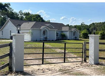 Charming single-story home with a gated entrance and lush greenery, creating a welcoming curb appeal at 13430 Ne 30Th Ct, Anthony, FL 32617
