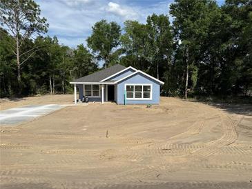 Charming single-story home with a blue exterior and white trim, nestled on a spacious lot at 14173 Se 41St Ter, Summerfield, FL 34491