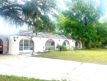 Unique home features a pool enclosure with arched entryways and stucco siding at 16850 Se 19Th Ct, Summerfield, FL 34491